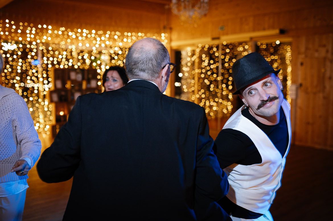 Wedding guests dance and celebrate on a dimly lit dance floor decorated with twinkling lights and chandeliers.