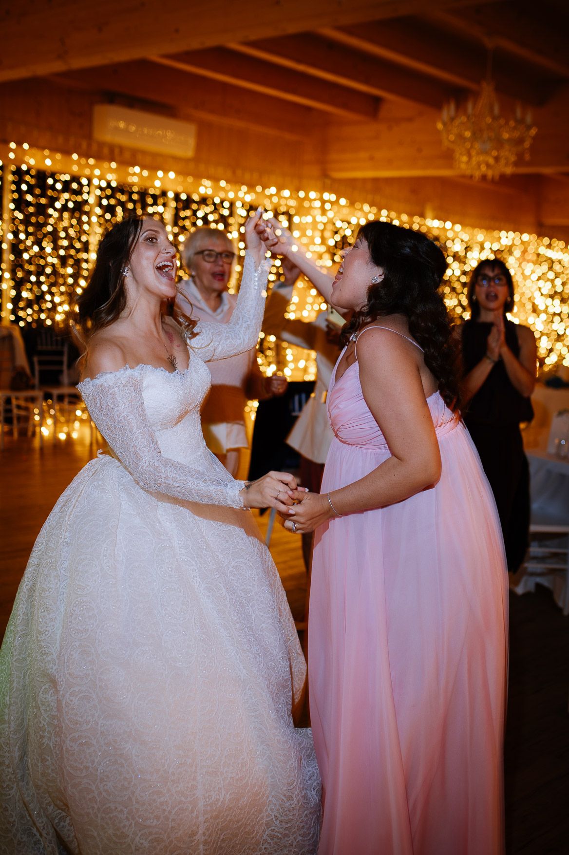 Wedding reception dance floor with string lights and rustic wooden beams creating a warm ambiance.