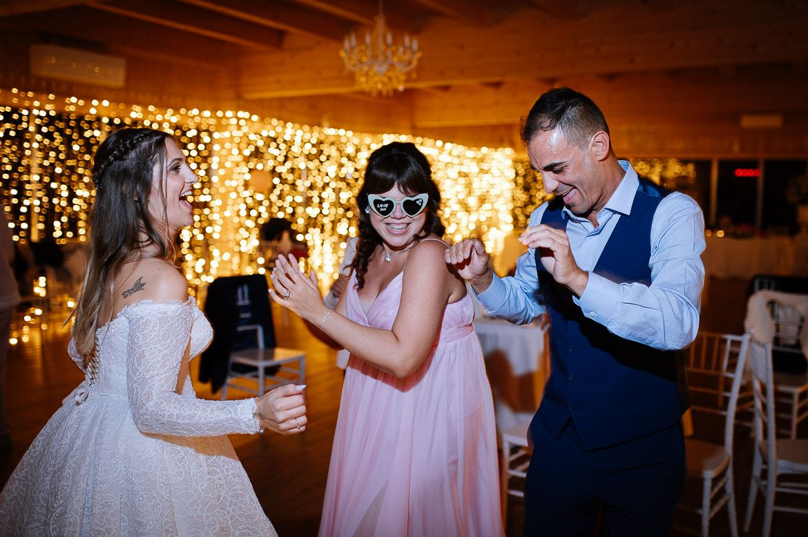 Wedding reception dance floor with string lights and chandeliers creating a warm, romantic atmosphere.