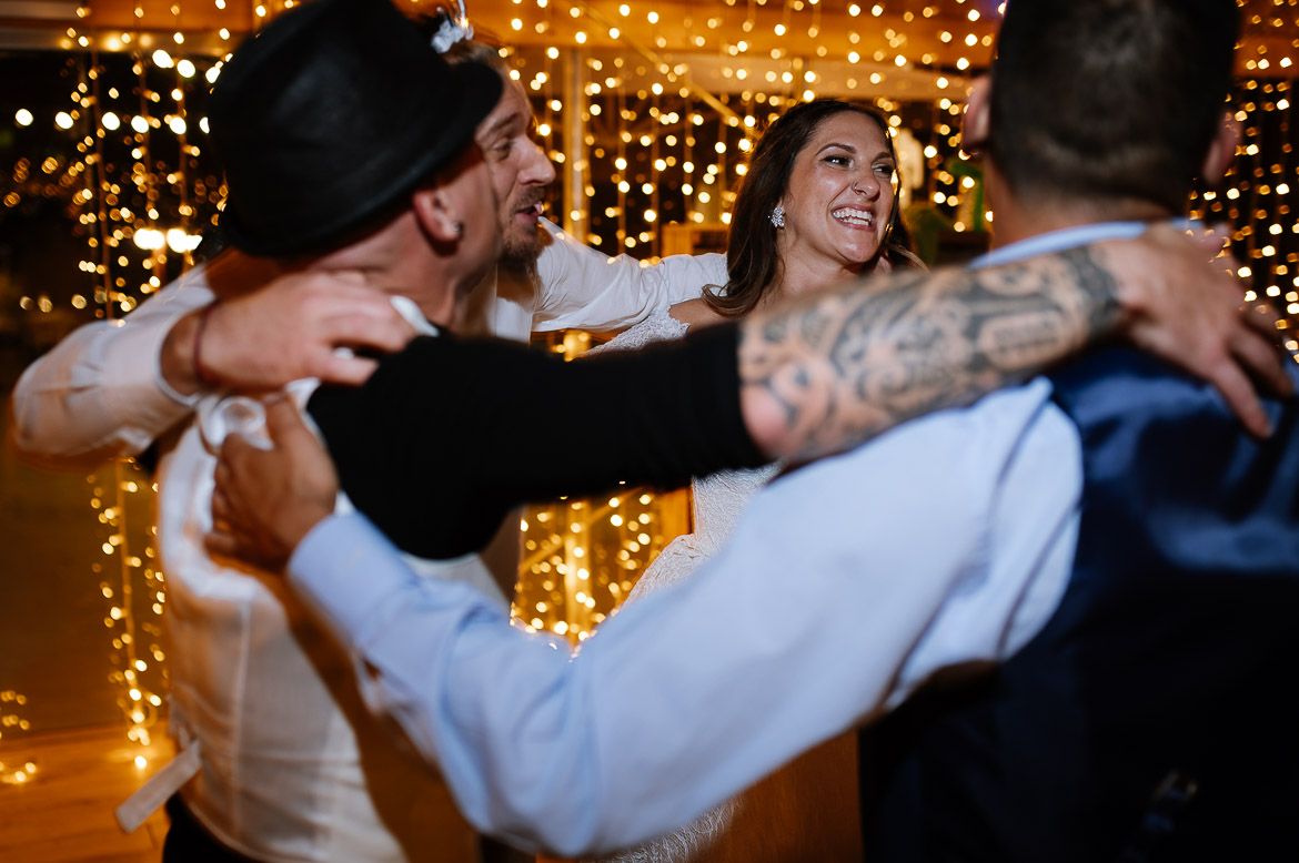 Couples dancing and celebrating at a wedding reception under twinkling string lights.