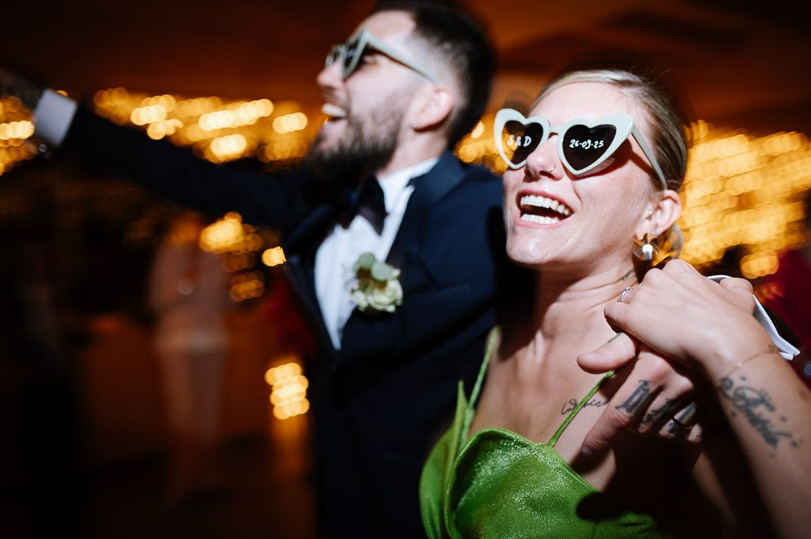 Party guests dancing and laughing together under atmospheric lighting at an evening celebration.