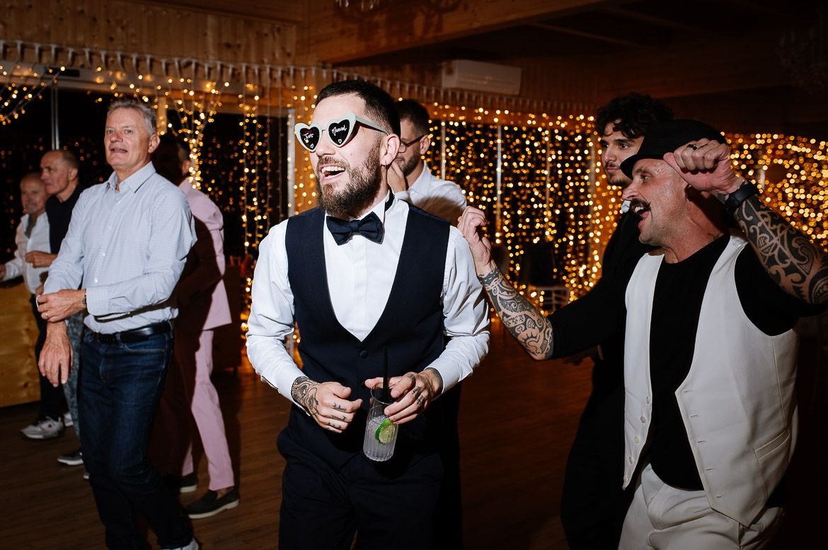 Wedding guests enjoying themselves on the dance floor under warm lighting at the reception.