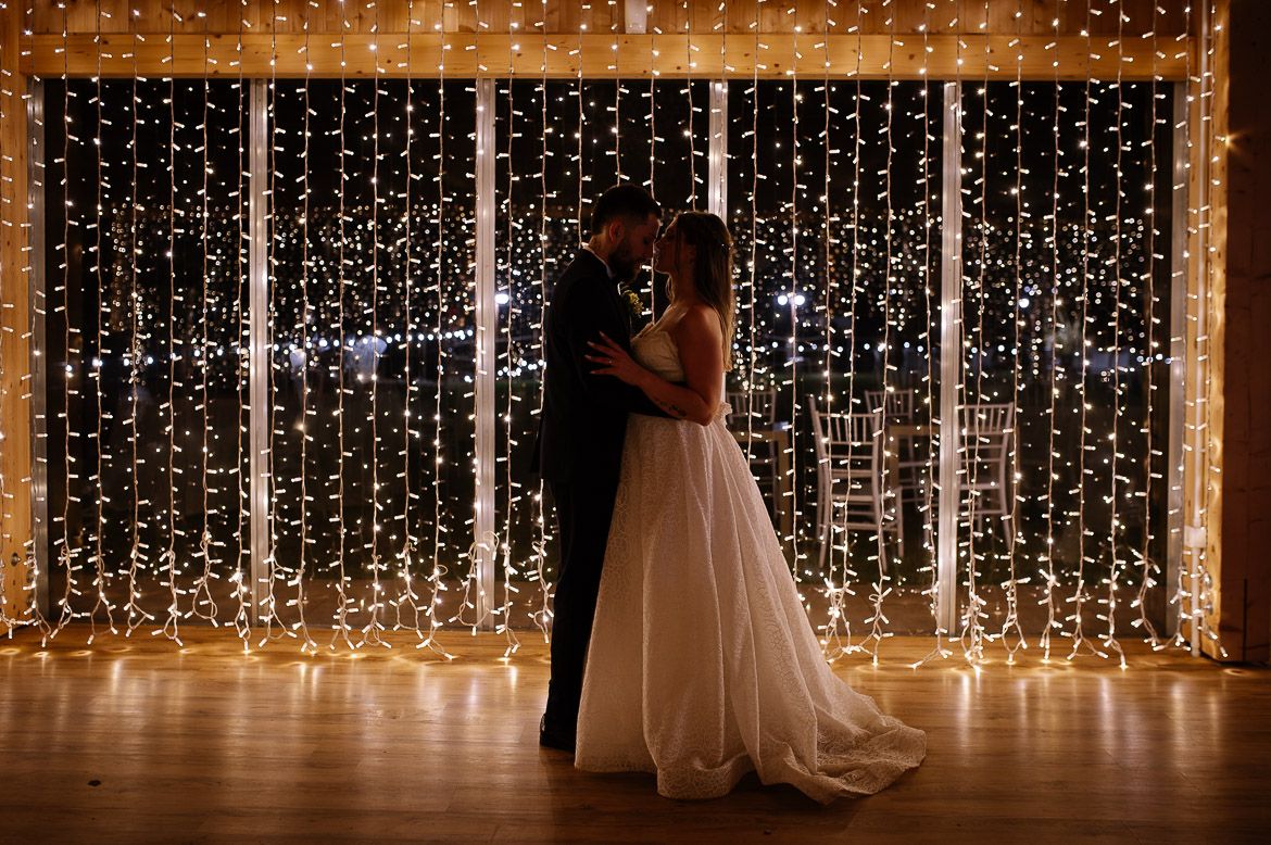 Elegant wedding reception venue with cascading fairy light curtains creating a magical backdrop for celebrations.