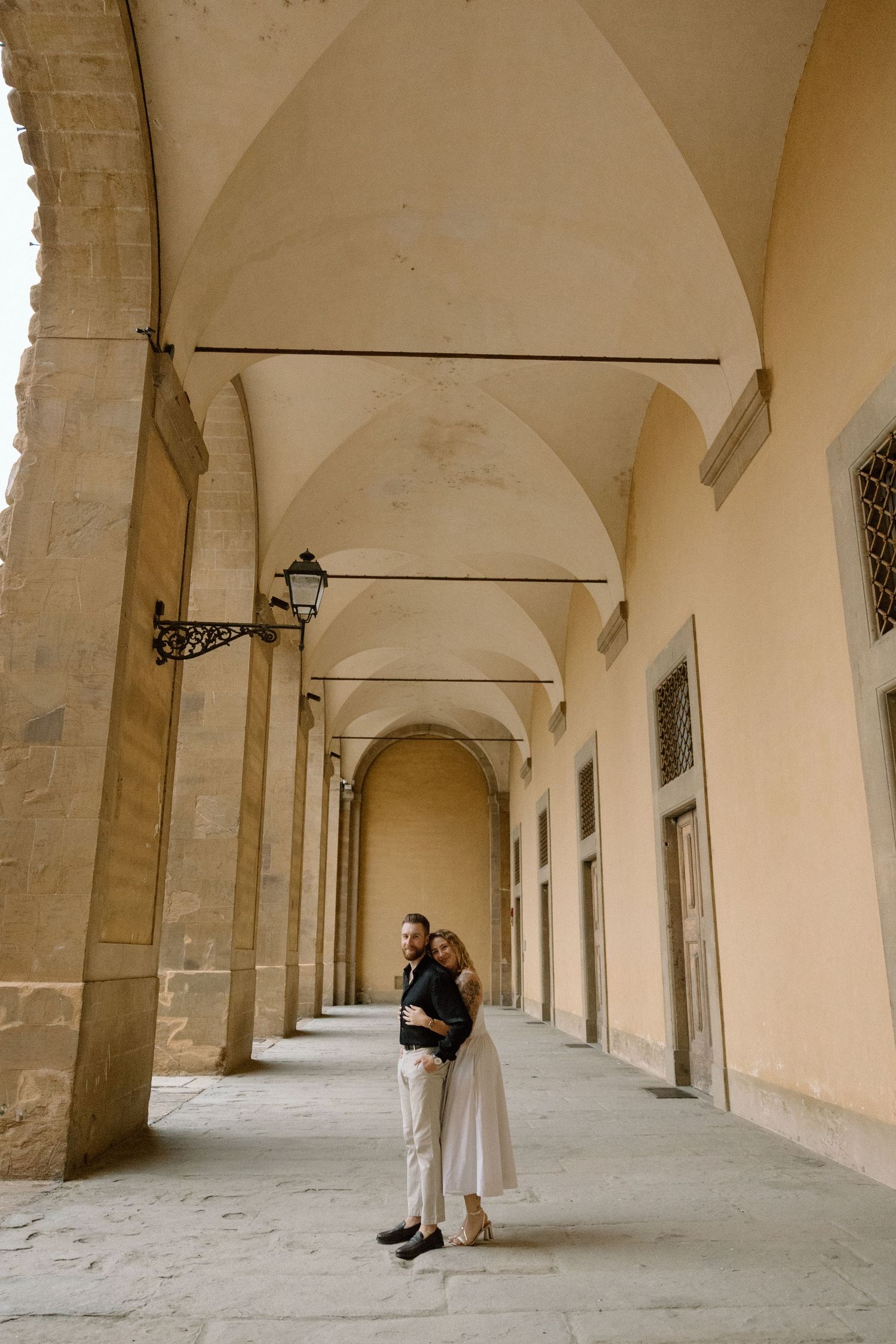 A series of elegant arched corridors in a historic Italian building with cream-colored walls and stone columns.