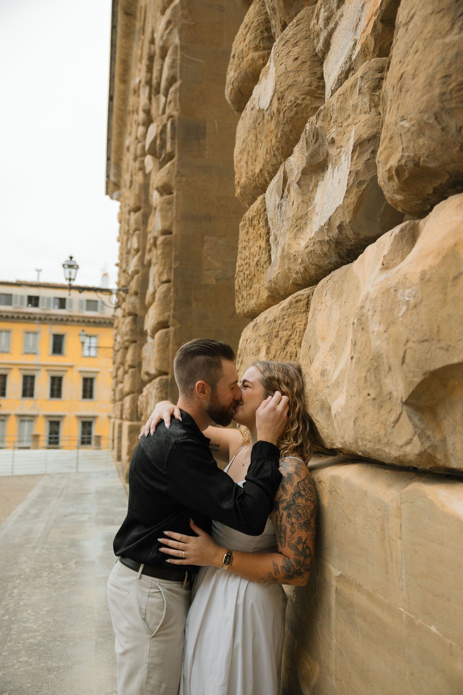 Couple sharing a tender moment against rustic stone columns in Florence.