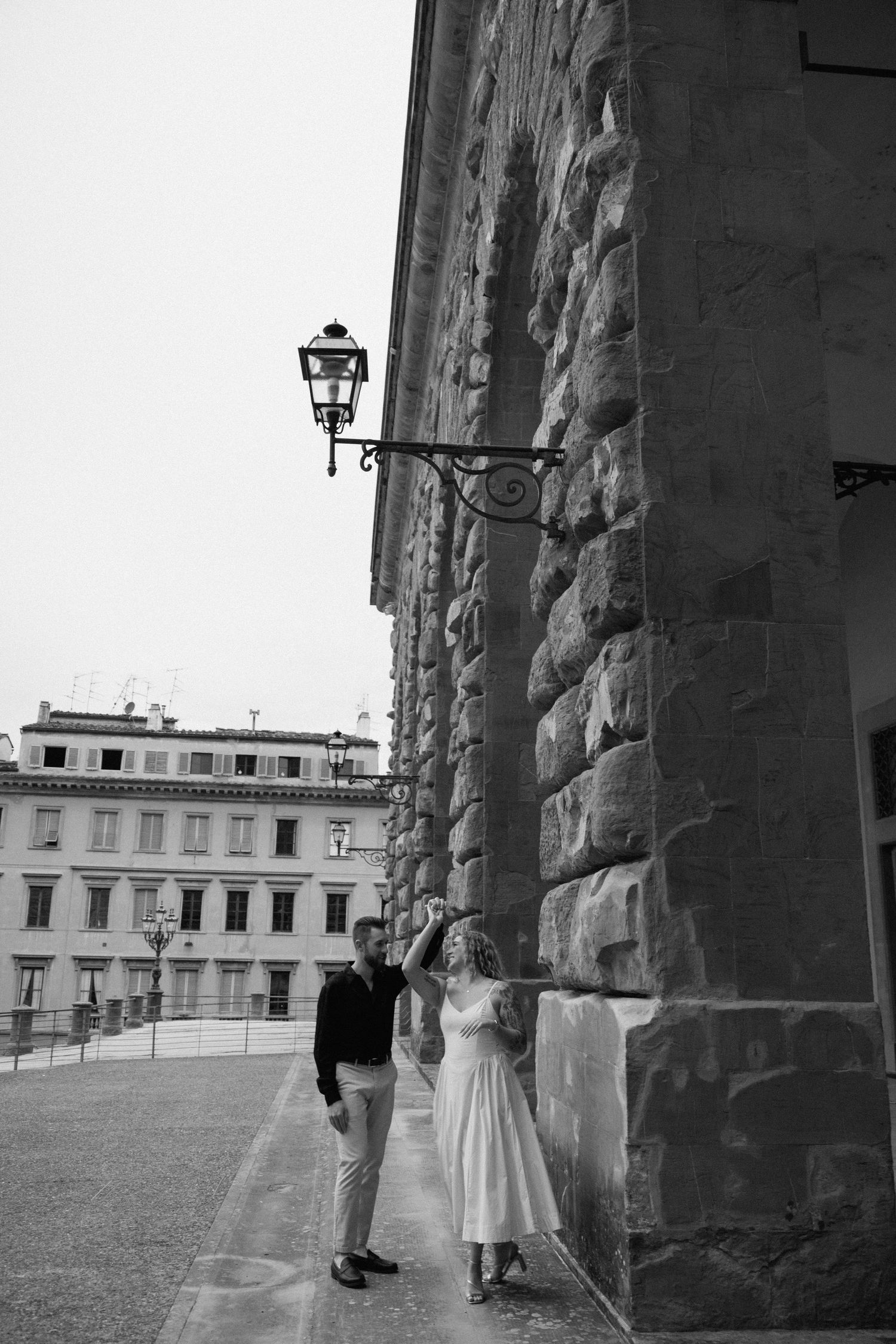 People standing under stone archways overlooking a historic European building exterior.