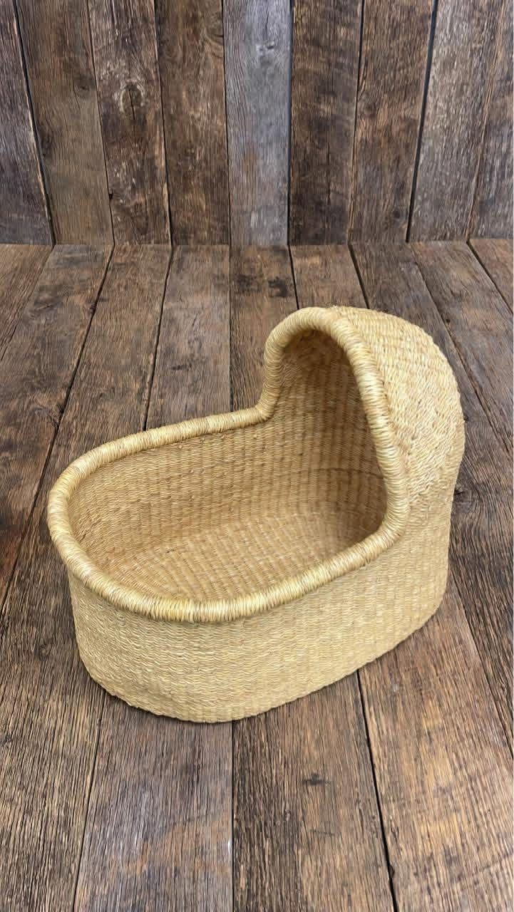 Handwoven natural straw baby Moses basket cradle with hooded canopy, oval shape, rustic wood background.