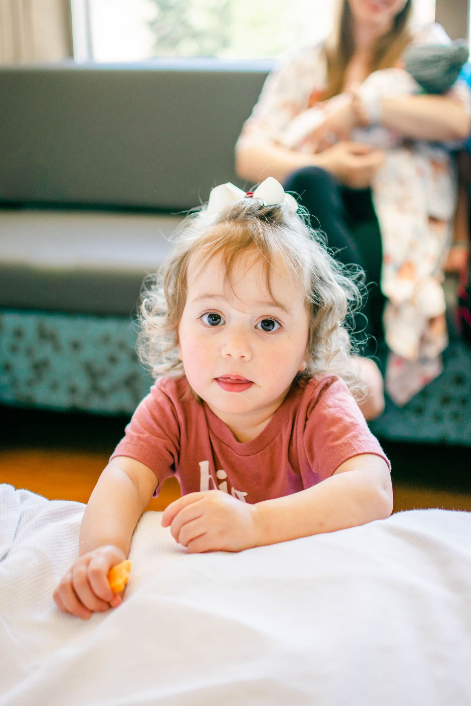 A series of candid shots showing a small child lying on white bedding in a warm, natural light setting.