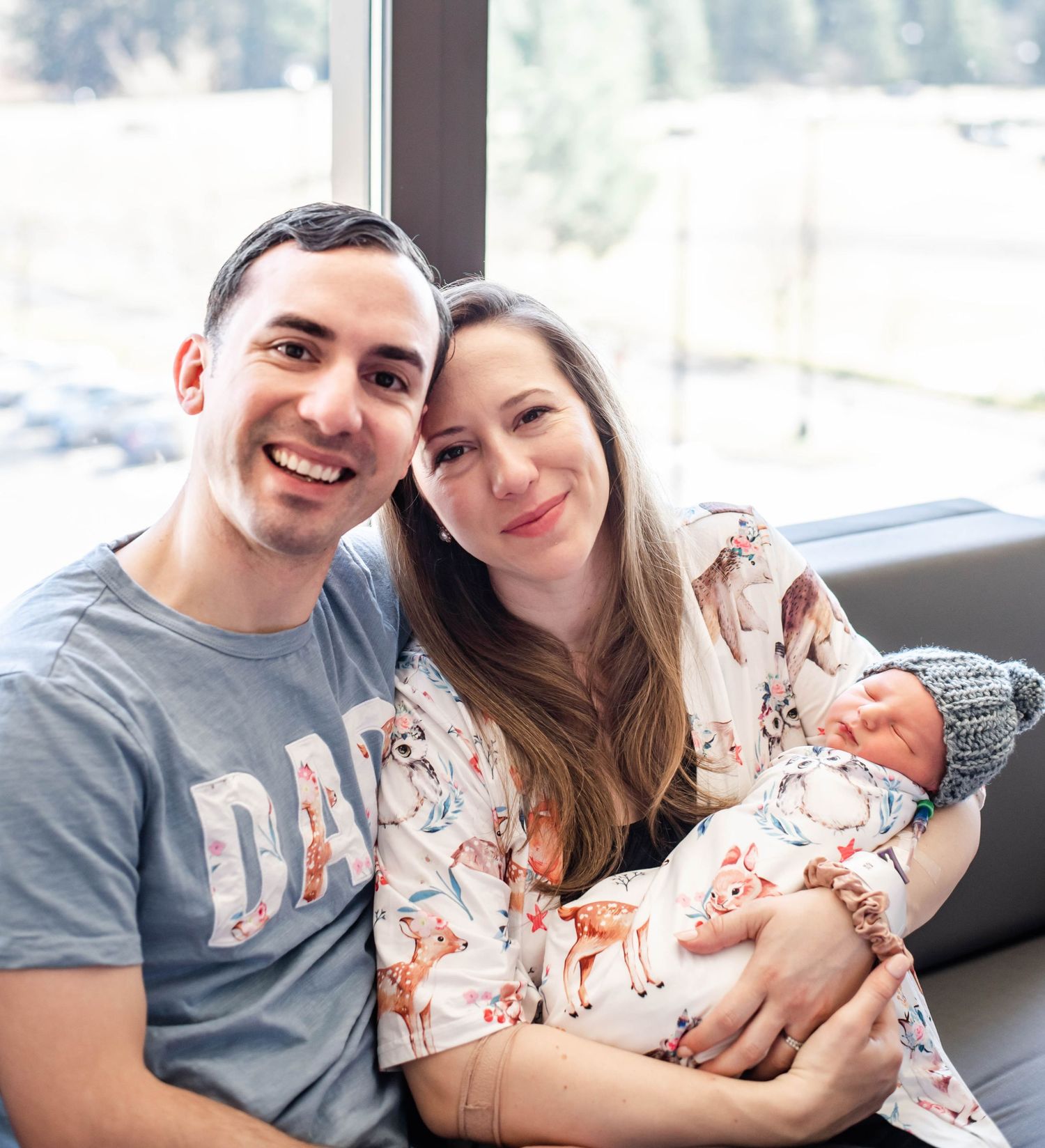 A couple sits together on a couch holding their newborn baby in a series of tender family moments.