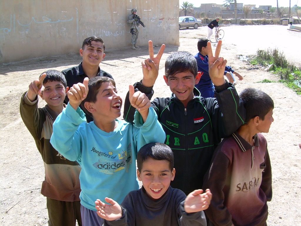 A group of people with joyful expressions raise their hands in celebration on a sunny day outdoors.