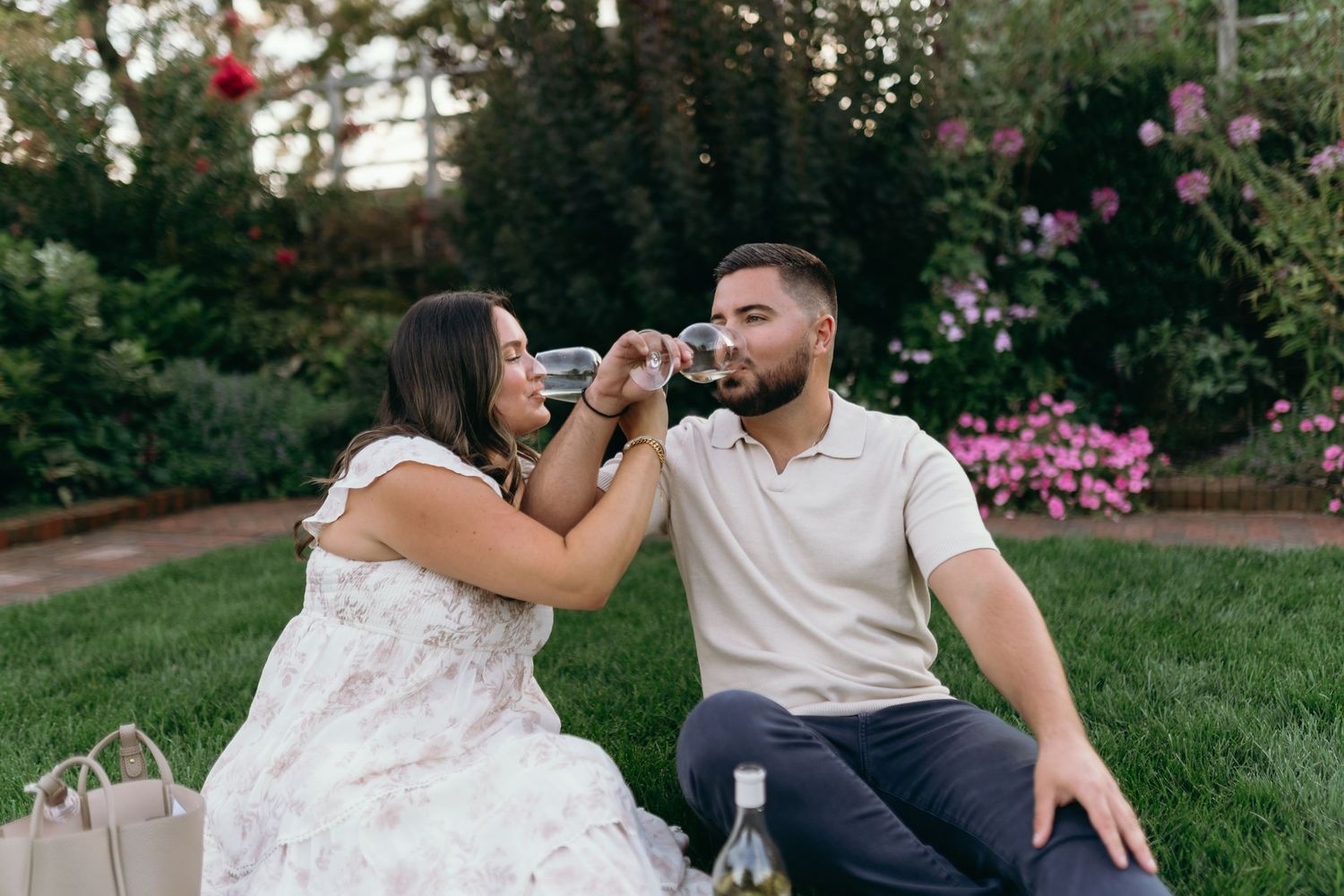 Romantic couple in white dress and casual wear share a passionate dip kiss in a sunlit meadow at golden hour.