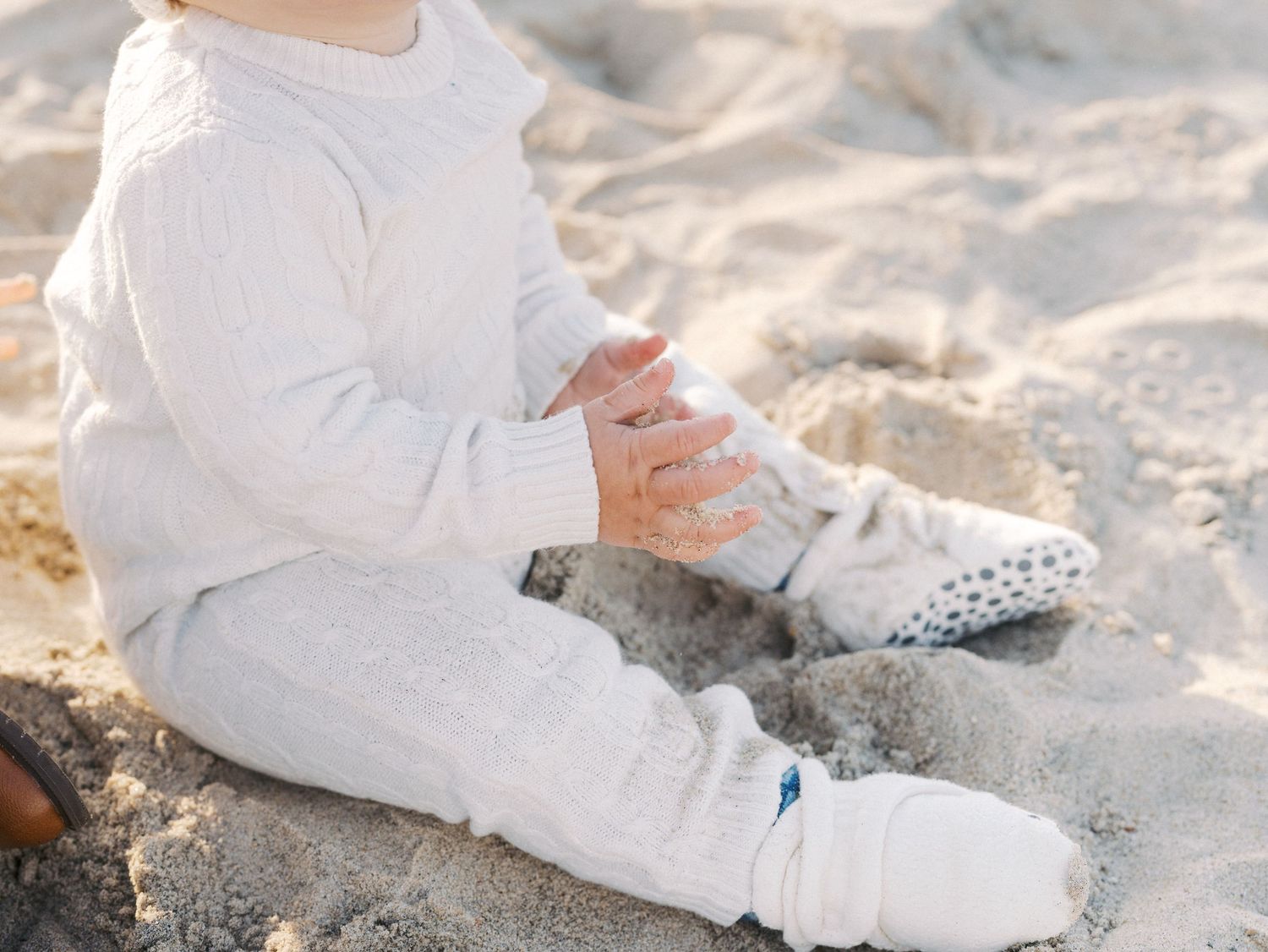 A baby boy exploring the sand through his fingers during a Monmouth County fall beach photo session.
