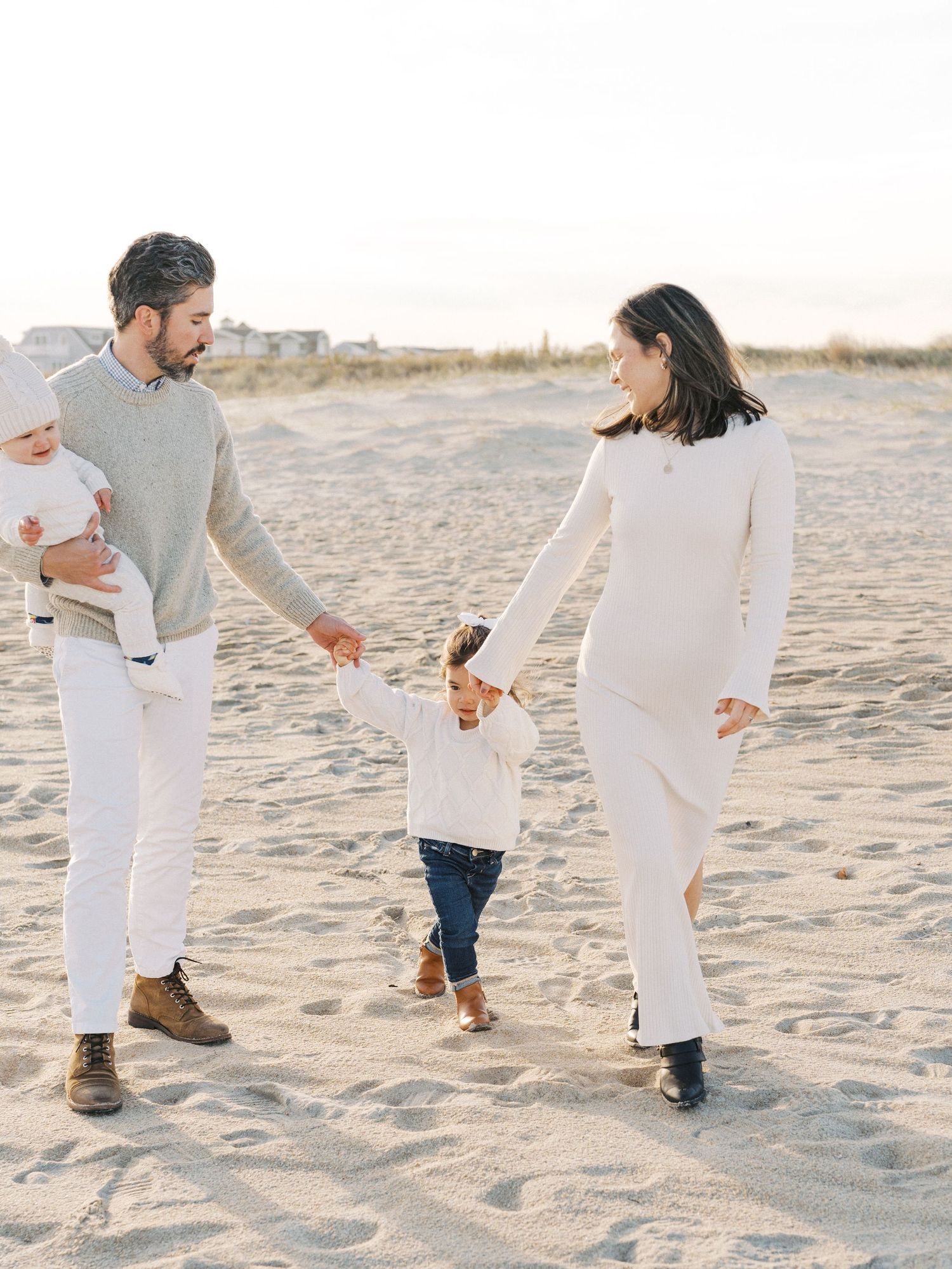 Family strolling by the ocean with soft fall light during a New Jersey beach photo session.