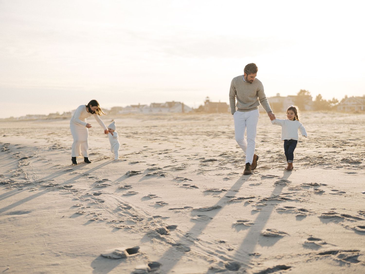 Parents smiling at their children while walking along the shoreline in autumn.