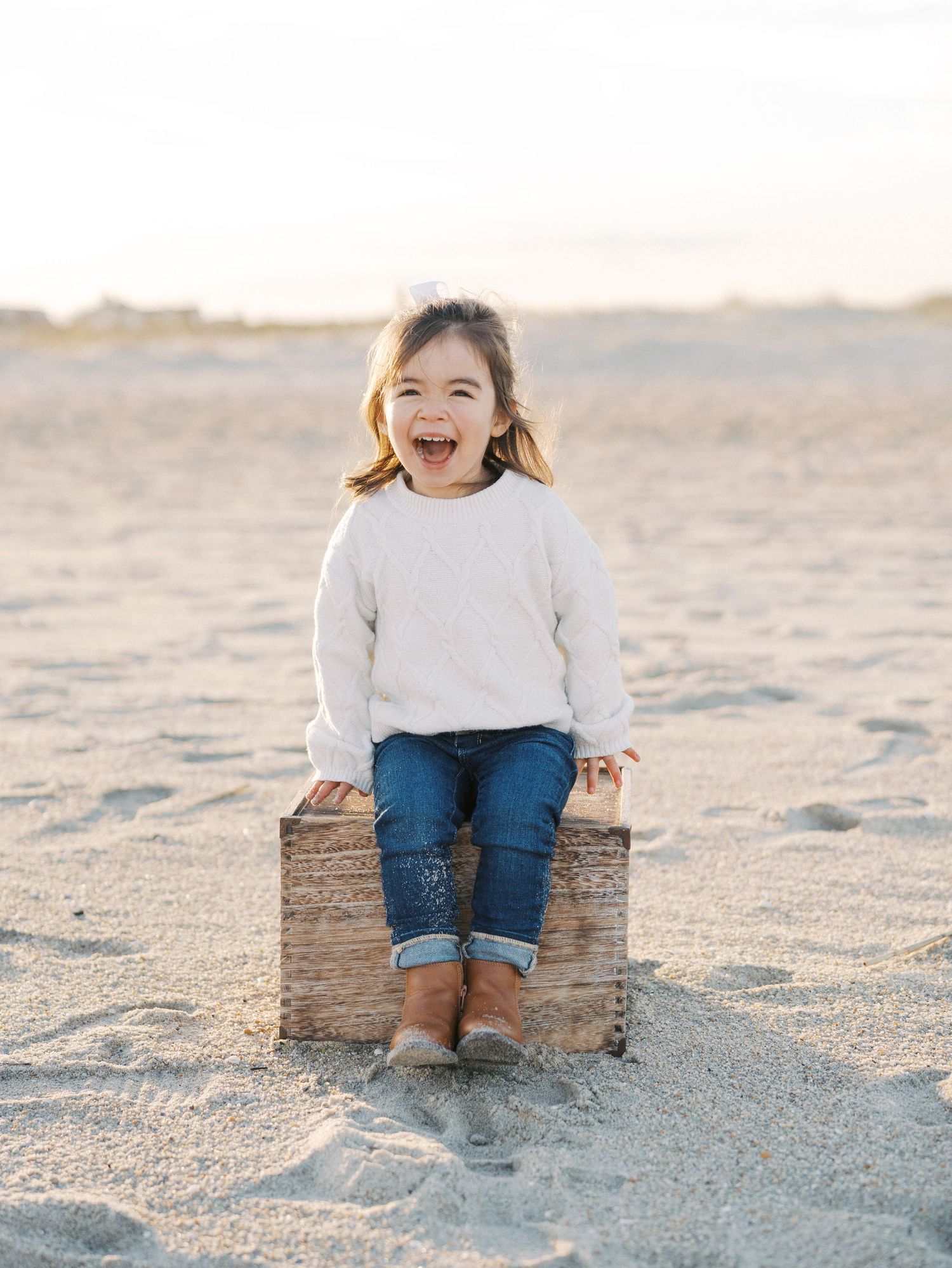 Little girl sitting on the beach during a fall photo session by lauren marie photography.