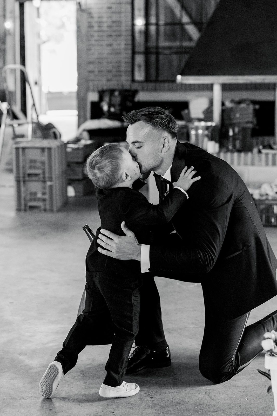 Two people in black suits kneel on the ground in a dramatic dance performance sequence.