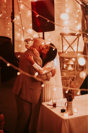 String lights create a warm ambiance at an indoor wedding reception venue.