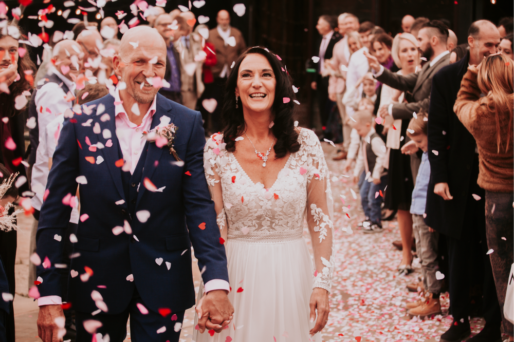 Wedding guests shower rose petals during a celebratory outdoor moment.