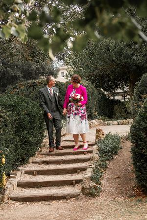 Two people descend stone steps in a garden setting with lush greenery.Bath Guildhall Wedding