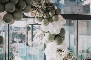Elegant wedding reception venue decorated with white and gray balloon arches and crystal chandeliers.