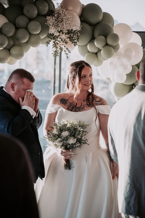 A wedding ceremony under a beautiful balloon arch with grey and white balloons and delicate floral accents.