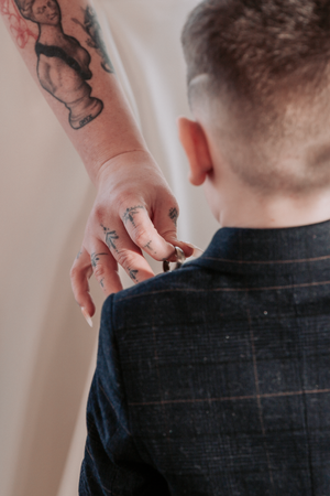 Close-up view of hands adjusting a black shirt collar against a light background.