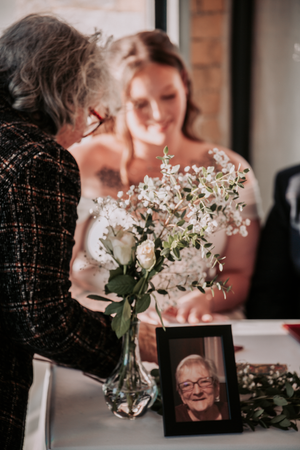 Wedding reception table features delicate white floral arrangements and framed photographs.