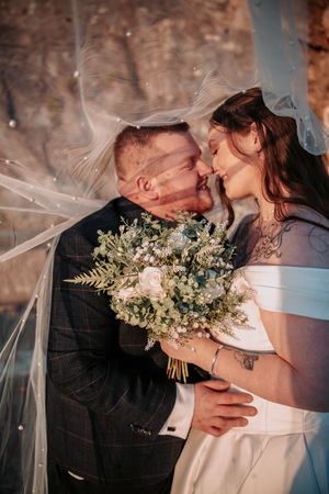 A romantic wedding moment captured with a flowing veil and delicate bouquet of white and green flowers.