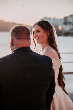 A couple shares an intimate moment during sunset on the beach with warm golden lighting.