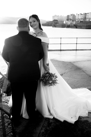 Silhouetted couple stands together on a balcony overlooking a cityscape.