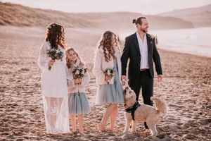 Family in coordinated outfits sharing tender moments together during sunset beach photoshoot.