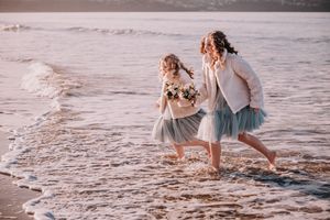 People strolling on a sandy beach with gentle waves lapping at the shore during golden hour.