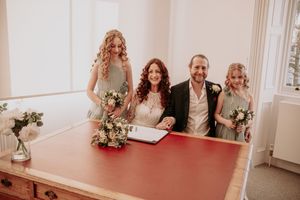 Wedding party seated at a long table in an elegant room with natural lighting.