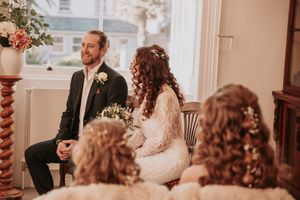 Wedding celebration scene in a warm-toned room with bookshelves and classic decor.