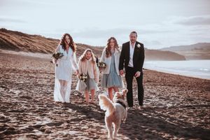 A wedding party walking along Three Mile beach with their golden doodle during their Elopement in Cornwall