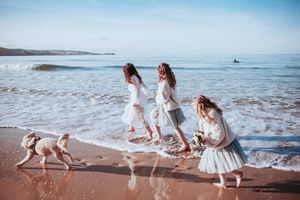 A series of photos showing people in white dresses playing and running along a sandy beach at sunset.