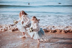 Children splashing and playing in the ocean waves during golden hour at an elopement on Three Mile Beach, Gwithian, Cornwall