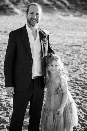 Black and white portraits of family members on beach in formal attire.