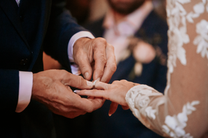 Close-up shots of wedding rings and hands during an exchange ceremony.