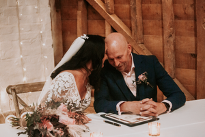 Interior of a rustic barn wedding venue with wooden beams and warm lighting.