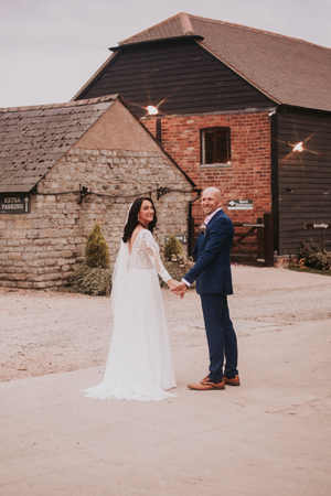 A couple shares their first look moment outside a rustic brick barn venue.