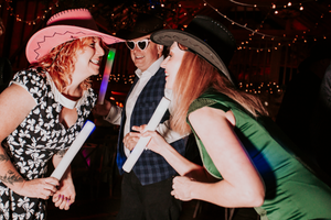 Guests dancing and celebrating at a wedding reception with string lights overhead.Direct Flash, Over Barn, Gloucester,