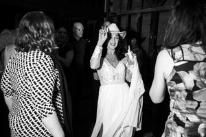 Wedding guests dance and celebrate together on a dimly lit dance floor at a reception party.