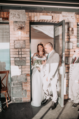 Wedding couple poses playfully in stone-walled venue with natural light.Pier One, Plymouth, Devon.