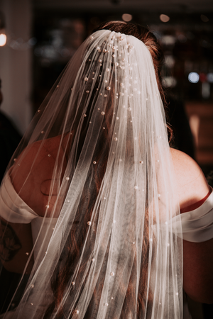 Delicate pearl-studded wedding veil detail in soft focus.