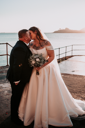 Romantic seaside wedding moment at sunset with coastal views.