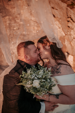 Intimate wedding moment with white bouquet against warm-toned backdrop.