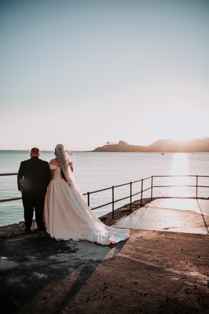 Newlyweds sharing a quiet moment by the ocean at sunset.