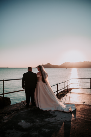 Silhouetted couple enjoying sunset views by coastal railing.