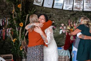 Wedding guests celebrate and embrace at a rustic outdoor reception venue.Porthleven, Cornwall